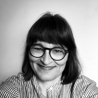 Headshot of a smiling Jayne Hall Cunnick wearing glasses and looking directly into the camera and stood face on